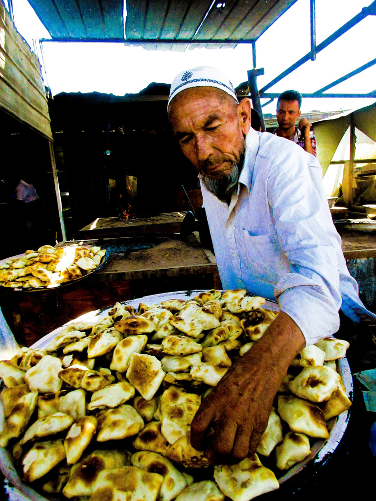 A street-food vendor at Kashgar livestock market, Xinjiang, China, churning out meat samsas for hungry auctioneers